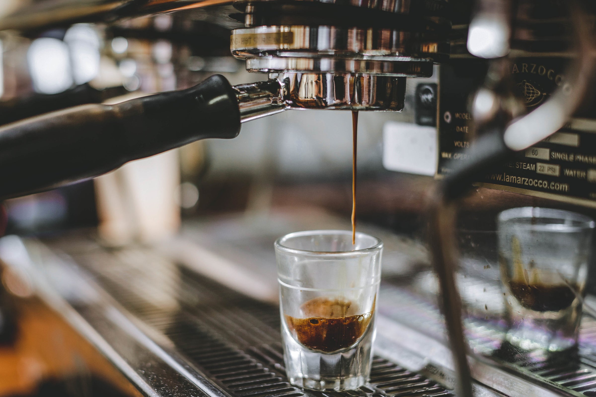 Pouring coffee stream from professional machine in cup. Barista